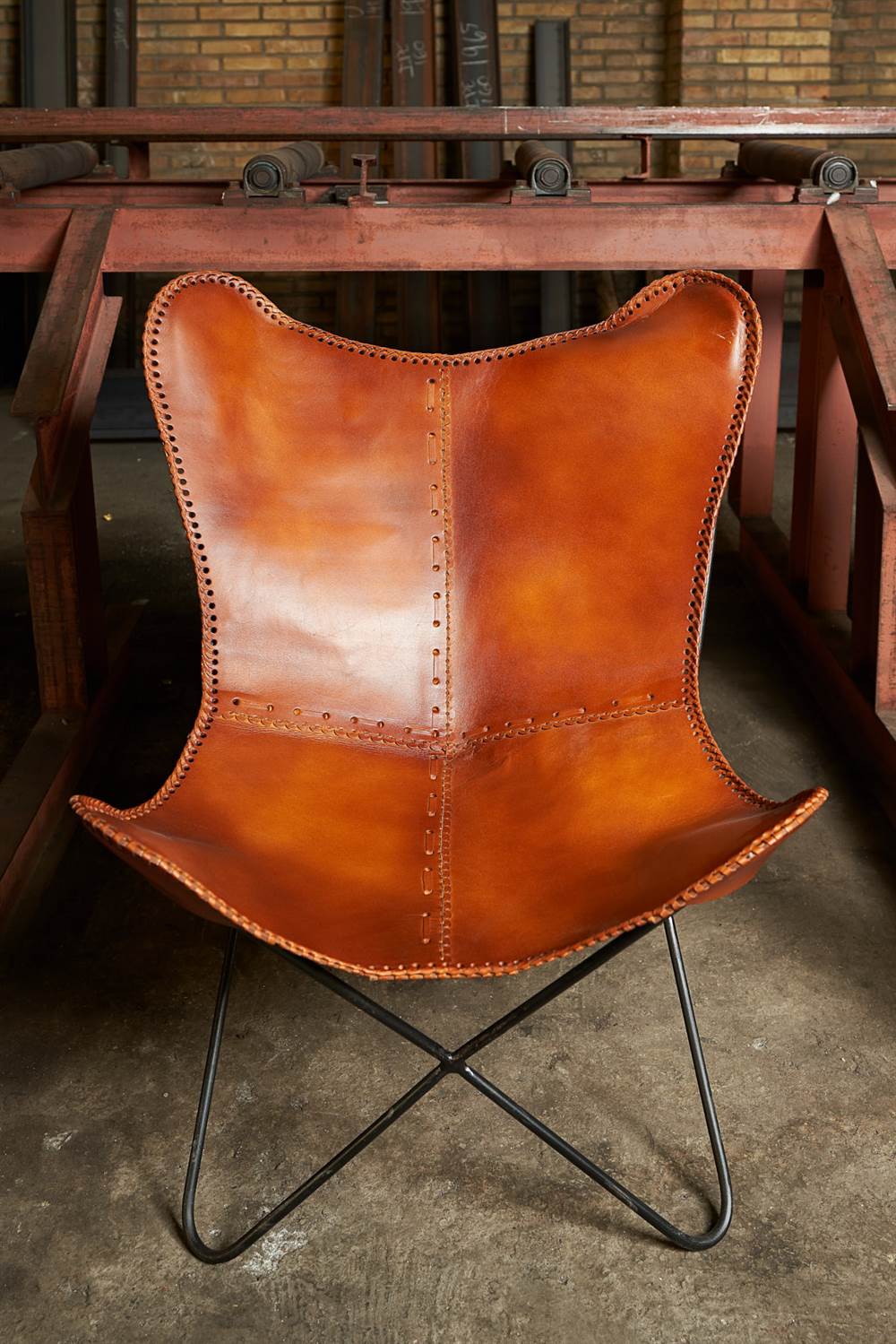BUTTERFLY CARAMEL DÉMONTABLE Chaise avec structure en tubes d'acier, finition noir, assise en forme de papillon en cuir. Réplique de la chaise BKF créée par Bonet, Kurchan et Ferrari Hardoy en 1938.